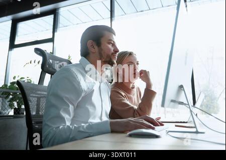 A man and a woman are looking at a computer monitor Stock Photo