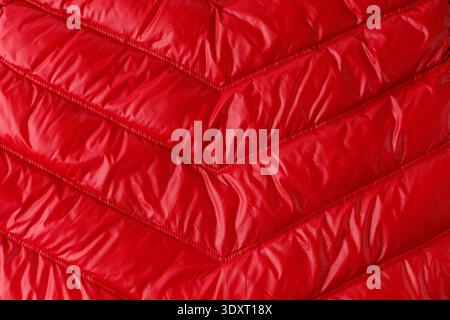 Texture of quilted red down jacket or coat as background. Detail of winter clothes. Stock Photo