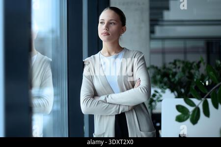 A woman in a business suit stands in front of a window Stock Photo