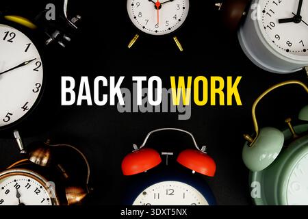 Back to Work text with alarm clock on black background Stock Photo