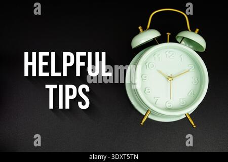 Helpful Tips text with alarm clock on black background Stock Photo