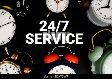 24 hr 7 Day Service text with alarm clock on black background Stock Photo