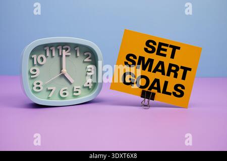Set Smart Goals text and alarm clock on blue and purple background Stock Photo