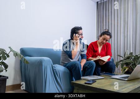 Couple having a phone call and taking notes, working on shared projects from home Stock Photo