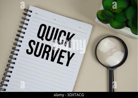 Quick Survey text on paper notebook with magnifying glass on beige leather background Stock Photo