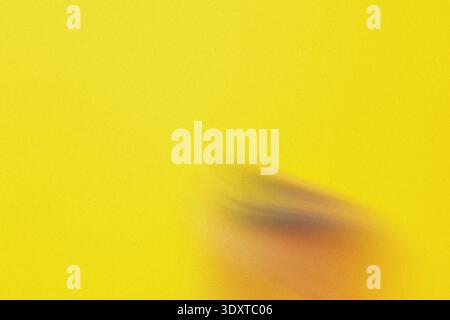 A blurred image featuring a hand against a bright yellow background creating a simple abstract design Stock Photo