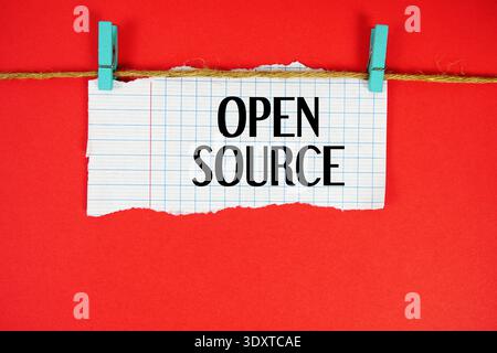 Open Source text written on rip paper with wooden clip on red background Stock Photo