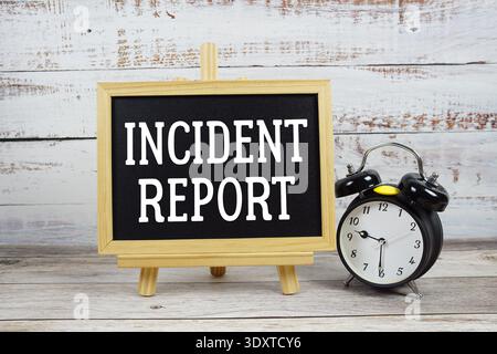 Incident Report text written on blackboard with alarm clock on wooden background Stock Photo