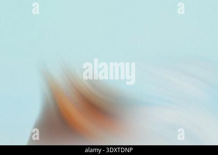 A blurry image showing a hand holding a pencil against a light blue background with soft lighting effect Stock Photo