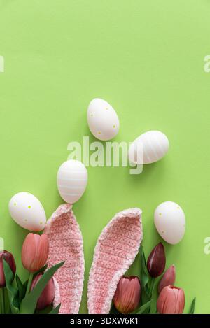 Easter Eggs with Bunny Ears and Tulips on Green Background. Spring Holiday Composition Stock Photo