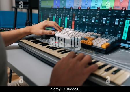 Close-up of music producer operating digital audio workstation with hands on midi keyboard and computer keyboard, editing sound tracks for audio Stock Photo
