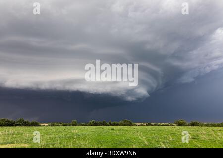 Dark storm clouds over a green grass field in Nebraska Stock Photo