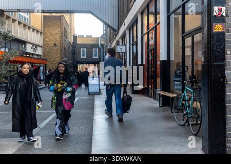 London, England, 12 December 2025,  People walking through a narrow pedestrian street in an urban district with brick buildings and shops. Brick lane Stock Photo