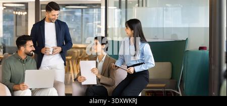Panoramic view of team collaborating, discussing project details in office Stock Photo