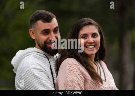 Happy young couple expressing joy, standing embraced connecting in nature Stock Photo
