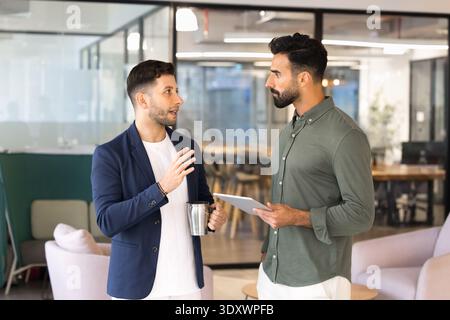 Male colleagues talking during work break in office Stock Photo