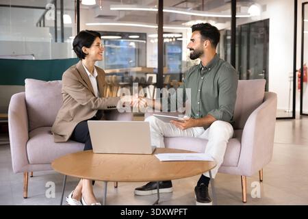 Smiling business people shaking hands in office Stock Photo