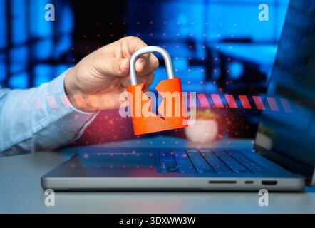 A cracked padlock in a man's hand over a laptop. Hacked security system and corporate data leakage threat highlighting cybersecurity breach and hacker Stock Photo