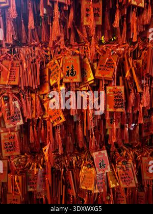 Red Chinese prayer tags with wishes and calligraphy hanging at temple, traditional symbols of luck and fortune, China. Stock Photo