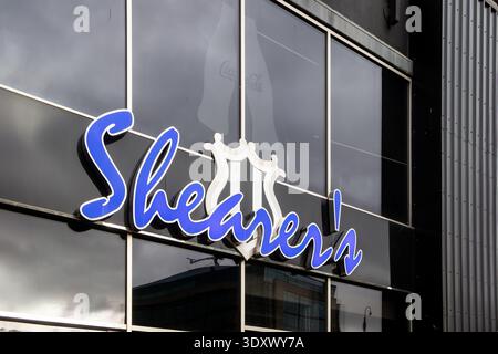 Close up of the illuminated Shearers sign with bright blue script lettering on dark storefront window newcastle united stadium Stock Photo