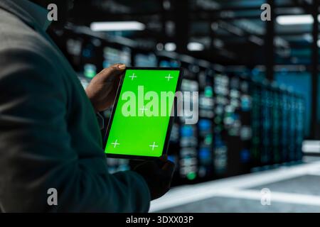 Close up of man in data center using green screen tablet to check for server performance issues. IT expert in server hub fixing errors slowing down hardware using chroma key device Stock Photo