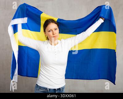 Sorrowful woman posing in studio with national flag of Sweden Stock Photo
