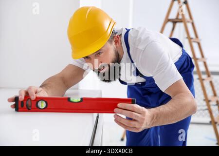 Worker measuring white dresser with building level indoors Stock Photo