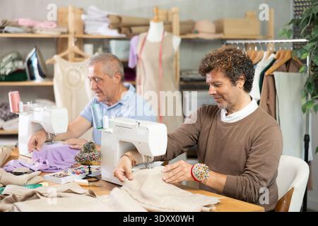 Two tailors sitting in a sewing workshop and working Stock Photo