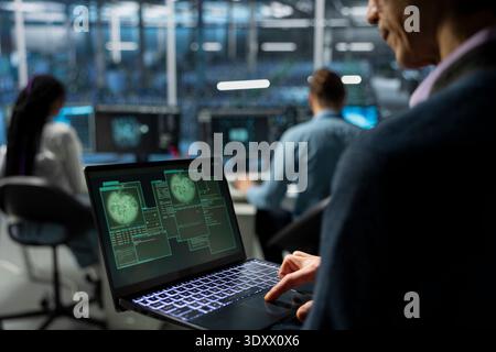 IT expert in server farm supporting international cloud services using notebook. Data center system administrator maintaining secure connectivity for global clients using laptop Stock Photo