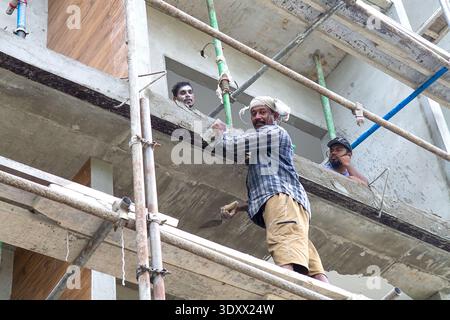 Maldives, Thoddoo - 16 Feb 2022: Local dark-skinned construction workers on scaffolding painting or plastering building facade on Thoddoo island Stock Photo