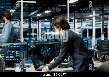 Software developer in server room office using device to review infrastructure diagnostics. Man in high tech data center analyzing performance data to maintain system uptime Stock Photo