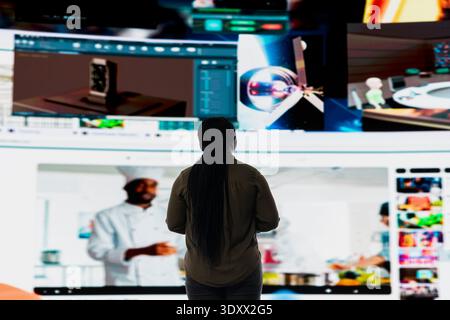 Woman browsing curated video recommendations on streaming service application projected on large screen. User enjoying free time exploring favorite online entertainment clips on videowall Stock Photo
