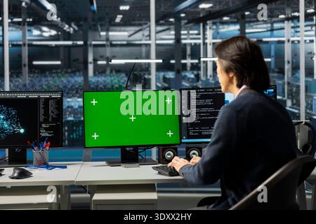 IT specialist using isolated screen PC in server room with infrastructure supporting data mining. Worker using mockup computer in data center to do maintenance on mainframes Stock Photo