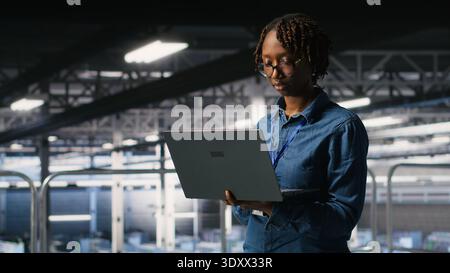 Data center system administrators doing maintenance tasks on laptop, ensuring optimal performance. IT specialists cooperating to review diagnostics and applying patches to server hub gear Stock Photo