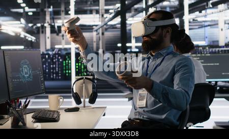 Admin using VR headset in data center to update server tech, configuring equipment using software tools. Server farm employee reviewing hardware analytics using virtual reality, camera A Stock Photo