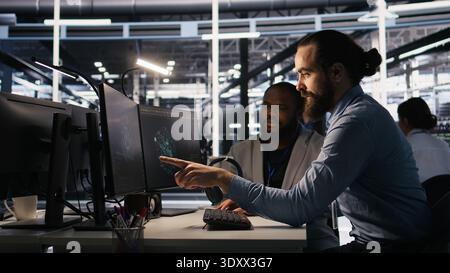 Lead data center engineer oversees team integrating AI automation tools during infrastructure maintenance. Worker under manager supervision uses machine learning models for operational tasks, camera A Stock Photo