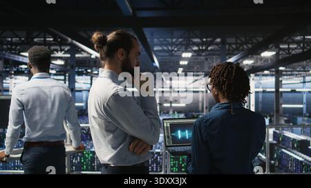 Data center manager overseeing work done by admin using neural network AI LLM visualization. Server farm team leader and worker overseeing rigs powering machine learning processes, Stock Photo