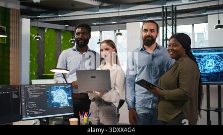 Team of programmers in office automating repetitive tasks using AI scripts on devices. Teamworking IT experts brainstorming, using artificial intelligence to speed up feature implementation, camera A Stock Photo