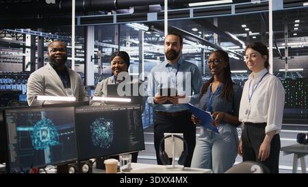 Happy data center engineering team members collaborating on neural network software development. Smiling server hub coworkers implementing machine learning technology in workplace, camera A Stock Photo