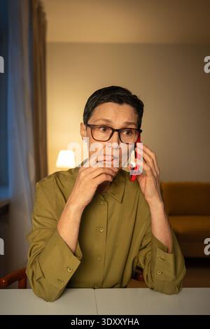 Nervous senior woman talking with scammers on smartphone, professional phone thefts manipulators. Stock Photo