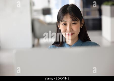 Young Asian office employee woman working at computer Stock Photo