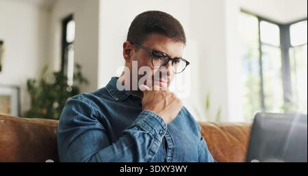 Laptop, thinking and man with remote work on sofa for article idea, story inspiration and editing. Freelancer, journalist and thoughtful with tech in Stock Photo