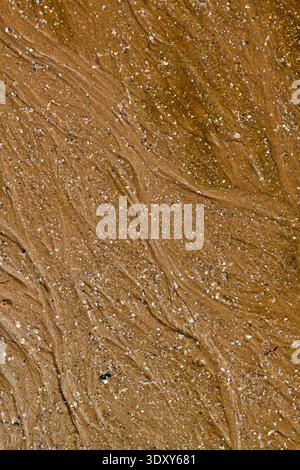 Detailed close-up of wet beach sand, natural textures and patterns created by water. Stock Photo