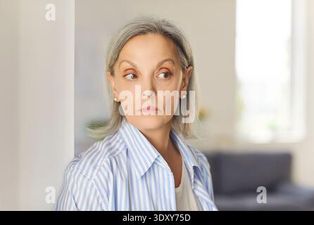 Portrait of senior elderly woman wearing casual clothes looking to the side standing at home. Stock Photo