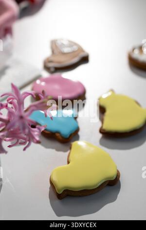 Colorful gingerbread cookies, shaped like an Easter bunny and other symbols, lie on a white surface, freshly decorated with bright icing. Stock Photo