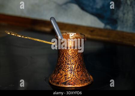 traditional copper cezve with spoon on stovetop Stock Photo