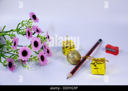 Pencil with sharpener, pink flowers and golden gift boxes isolated on white background. Creative still life concept for education, stationery supplies Stock Photo