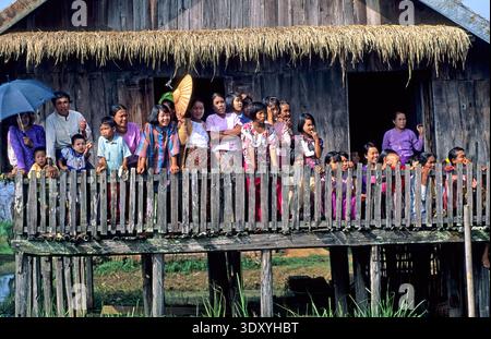 Crowds gather on a wooden platform overlooking Inle Lake during the festival. People watch festivities and interact with each other. Stock Photo