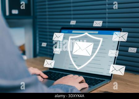 Email security concept. Person using laptop and shield icon for data protection. User checking inbox with encrypted firewall technology for corporate Stock Photo
