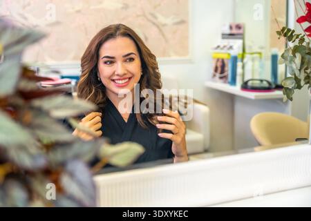 Happy woman experiencing new hairstyling in salon Stock Photo